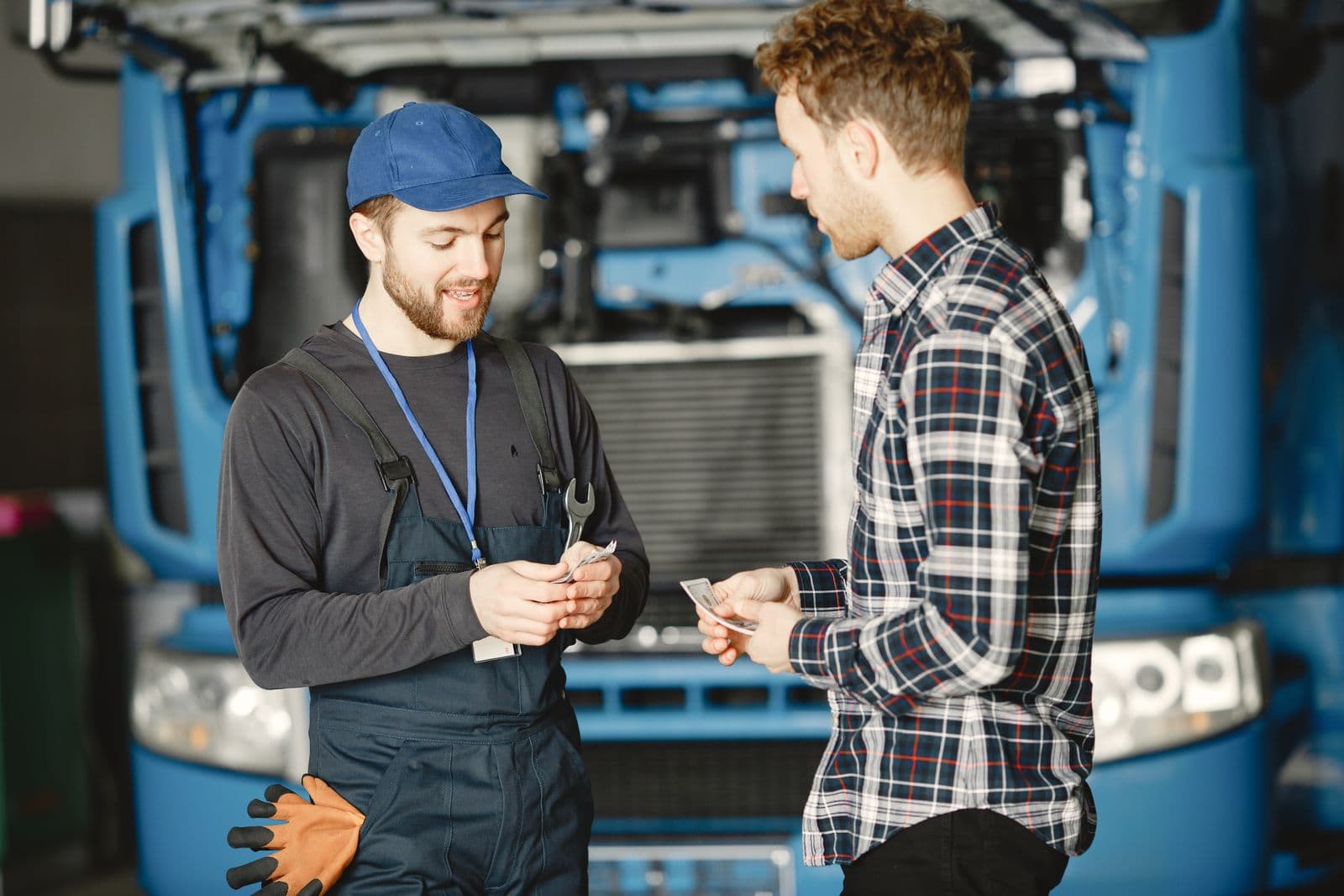A mechanic in a cap being paid by a customer after a repair