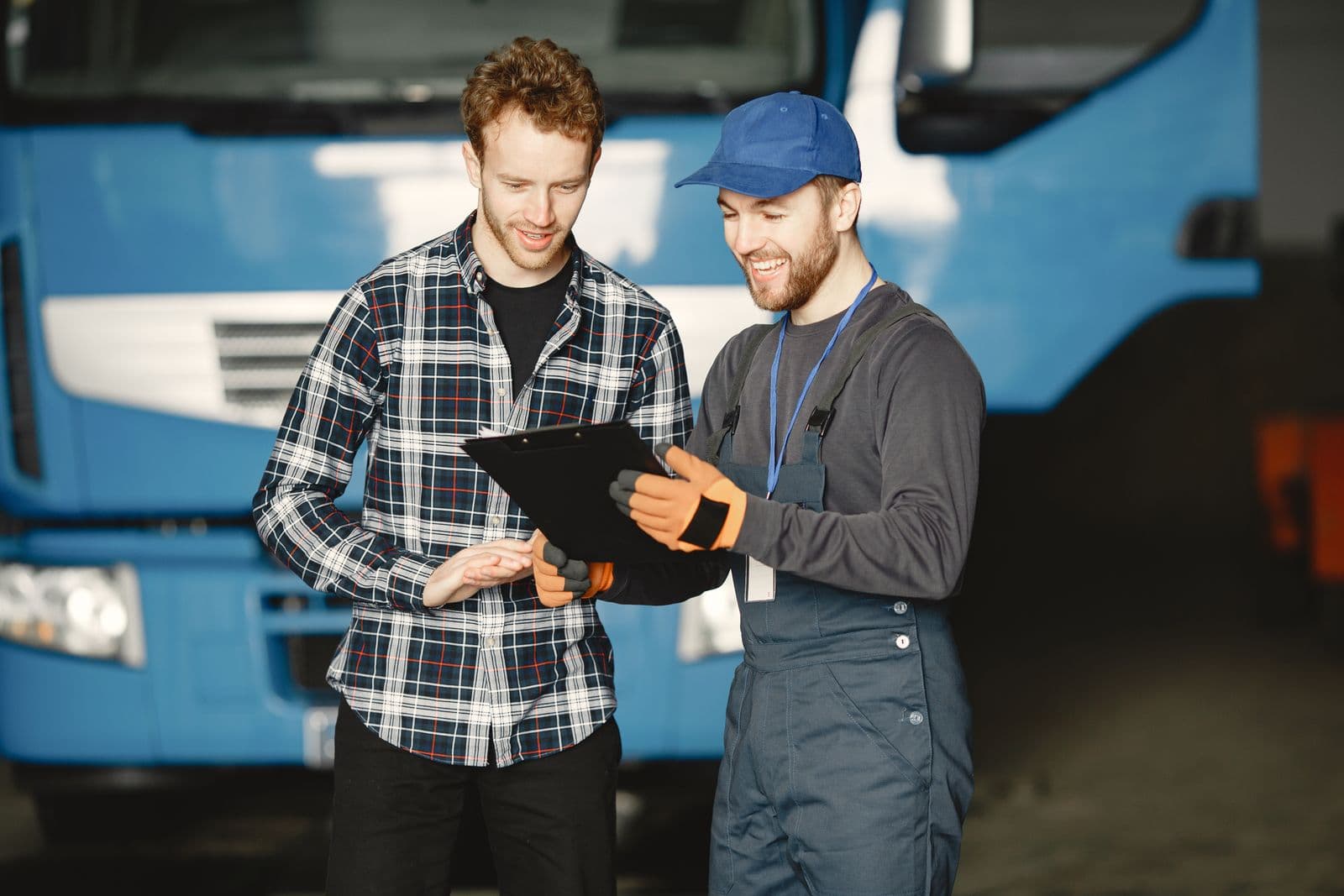 A mechanic going over a quote on a clipboard with a customer in the garage